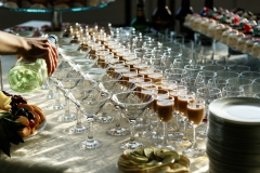 Man pours martini in cocktail glasses on dinner table